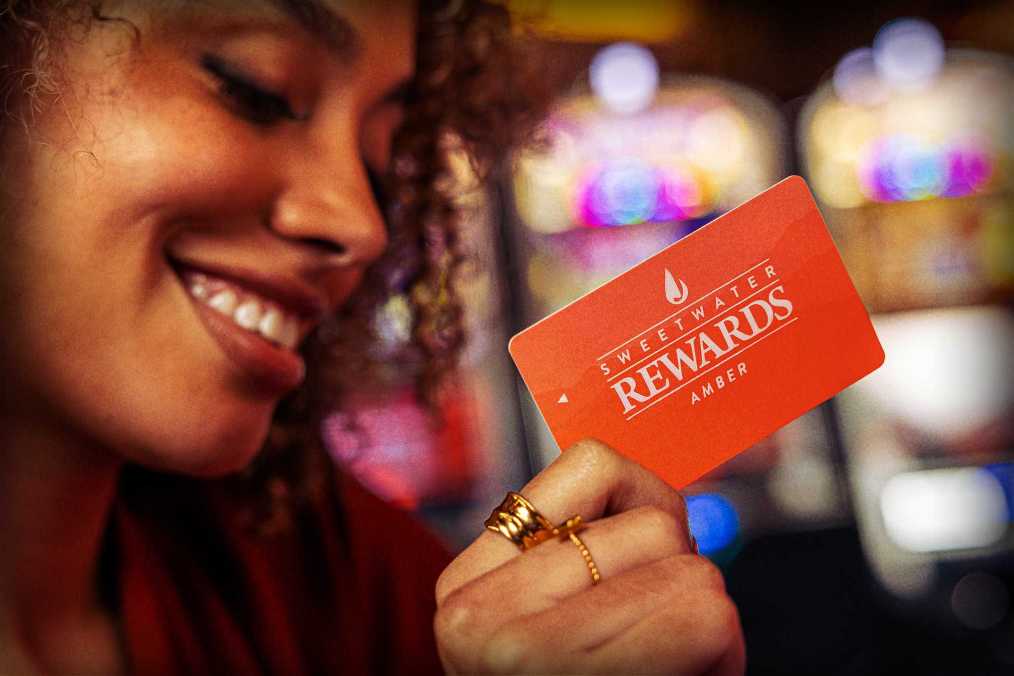 Woman holding a Sweetwater Rewards Amber card